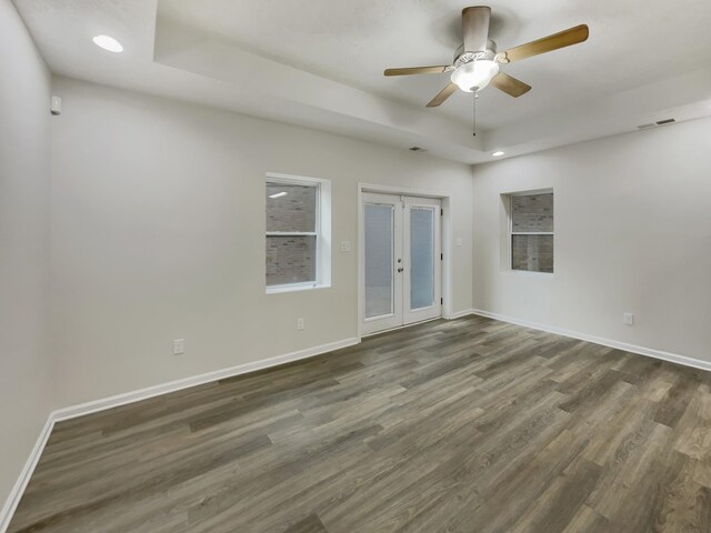 unfurnished room with french doors, recessed lighting, a raised ceiling, wood finished floors, and baseboards