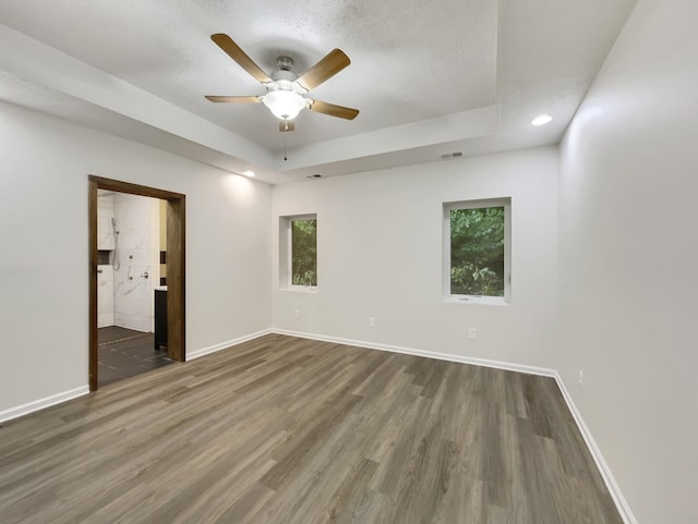 unfurnished room featuring wood finished floors, a raised ceiling, visible vents, and baseboards