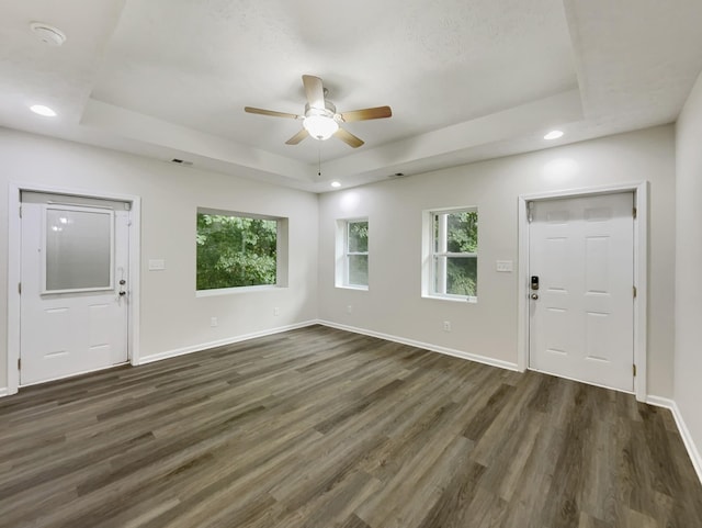 entrance foyer featuring dark wood-style floors, a tray ceiling, recessed lighting, and baseboards