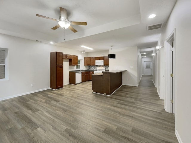 kitchen with white appliances, baseboards, visible vents, wood finished floors, and a peninsula