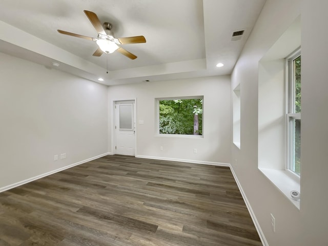 unfurnished room featuring a tray ceiling, visible vents, dark wood finished floors, and baseboards