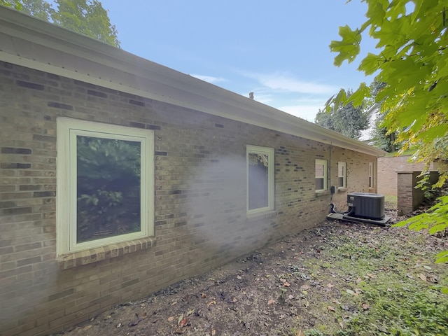 view of side of home featuring central AC unit and brick siding