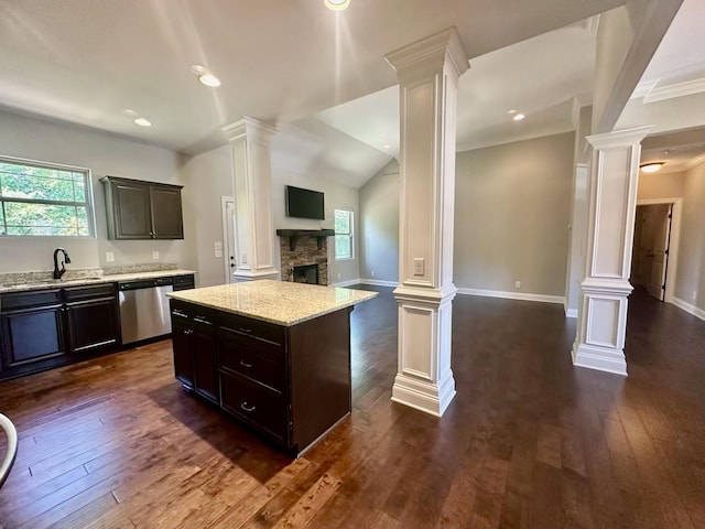 kitchen featuring stainless steel dishwasher, sink, a center island, dark hardwood / wood-style floors, and a stone fireplace