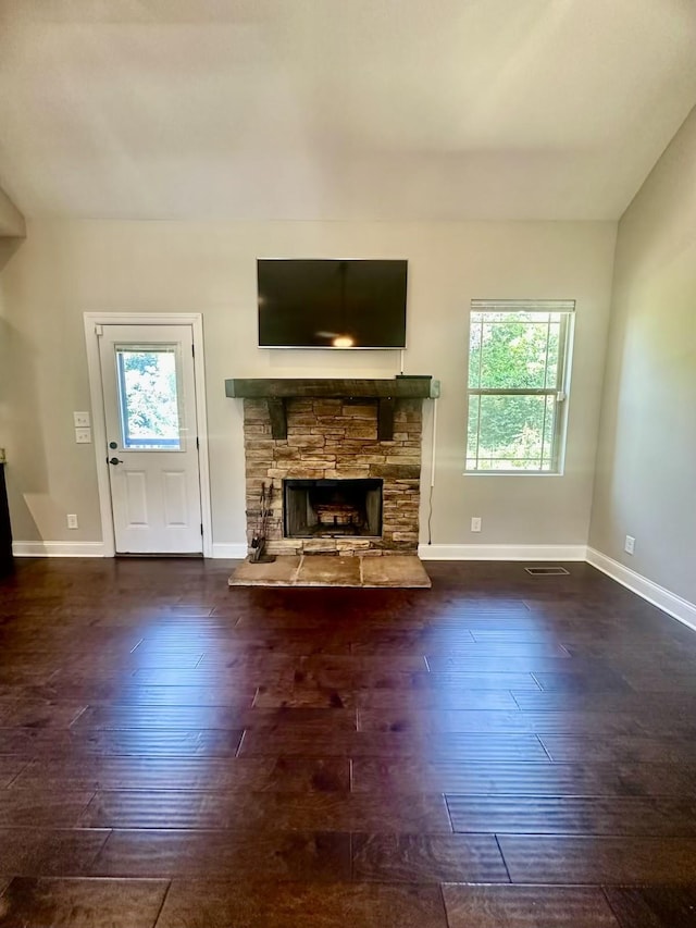 unfurnished living room featuring dark hardwood / wood-style floors, a healthy amount of sunlight, and a fireplace