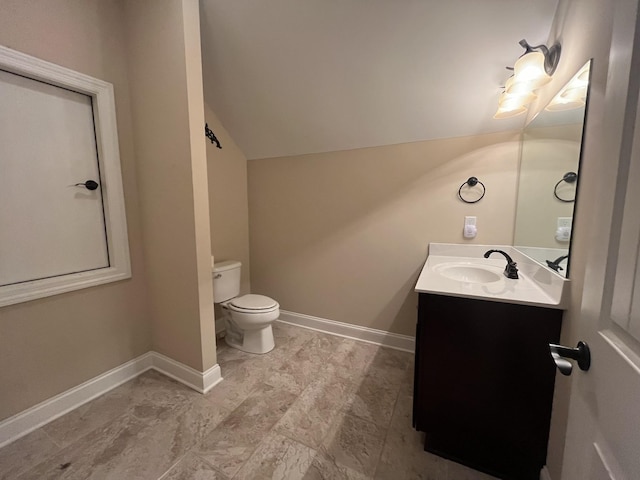 bathroom with vanity, toilet, and lofted ceiling