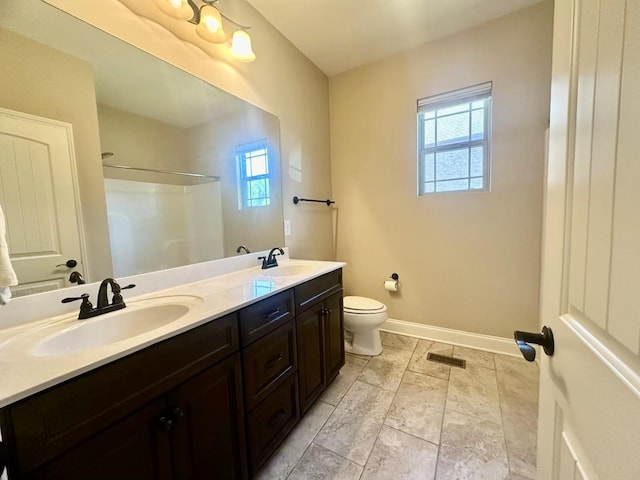 bathroom featuring a shower, vanity, toilet, and a healthy amount of sunlight