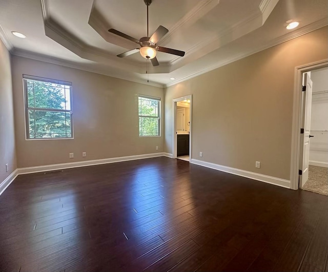 spare room with a tray ceiling, ceiling fan, a healthy amount of sunlight, and dark hardwood / wood-style floors