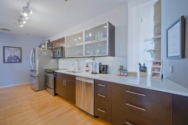 kitchen with light hardwood / wood-style flooring, tasteful backsplash, stainless steel appliances, sink, and rail lighting