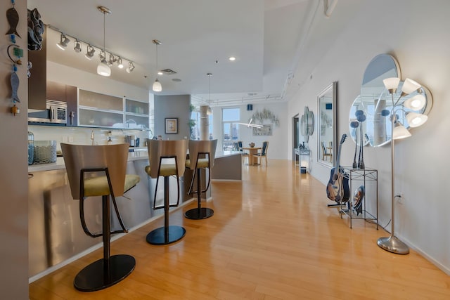 kitchen featuring a chandelier, pendant lighting, light wood-type flooring, rail lighting, and backsplash