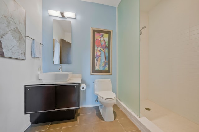 bathroom featuring vanity, tiled shower, toilet, and tile patterned floors