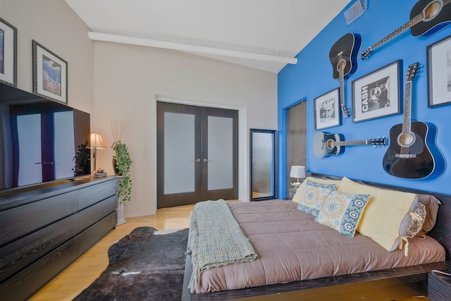 bedroom with vaulted ceiling, french doors, and hardwood / wood-style floors