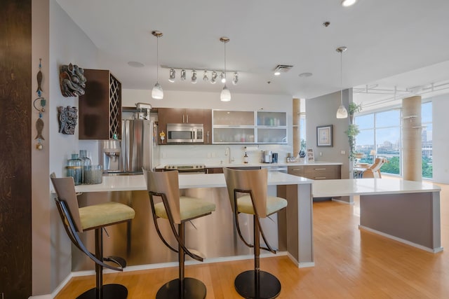 kitchen featuring stainless steel appliances, a breakfast bar area, tasteful backsplash, and light wood-type flooring