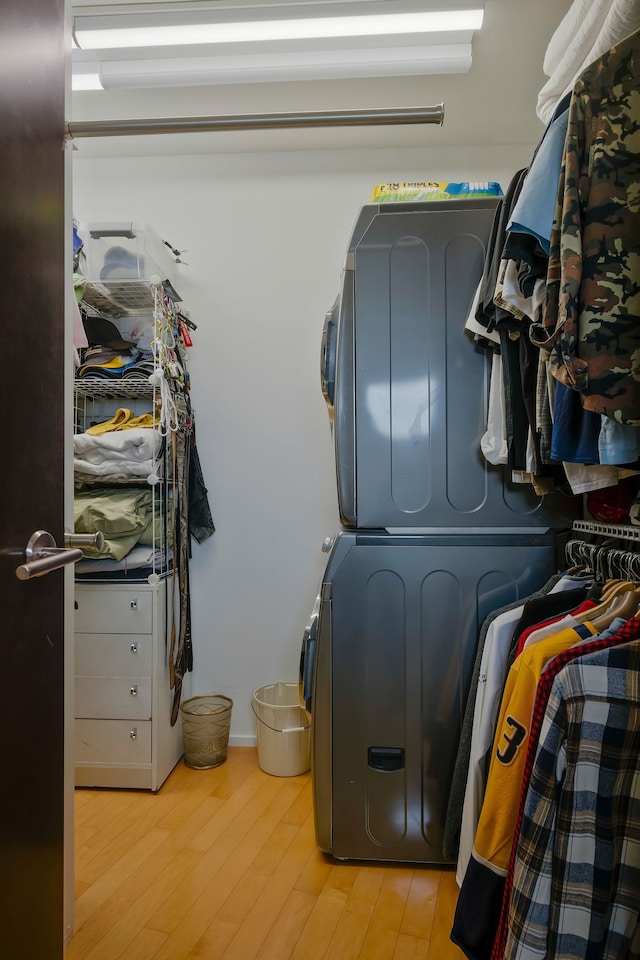 clothes washing area with stacked washer and dryer and light wood-type flooring