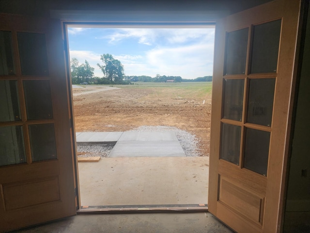 entryway with concrete floors, a rural view, and a healthy amount of sunlight