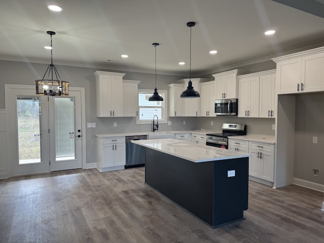 kitchen featuring sink, stainless steel appliances, a kitchen island, pendant lighting, and white cabinets