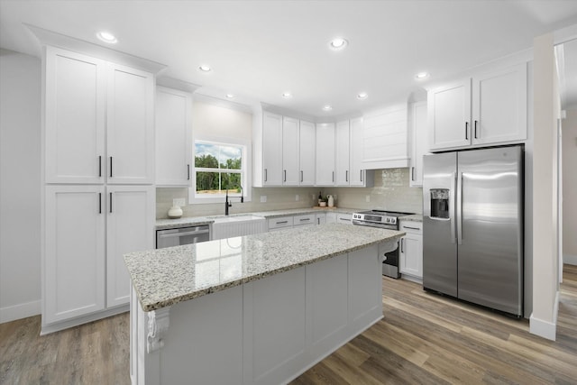 kitchen with white cabinets, a center island, custom range hood, and appliances with stainless steel finishes