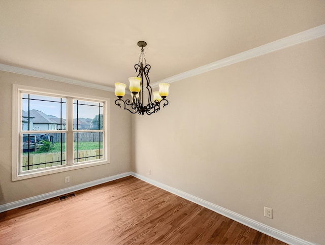 empty room with hardwood / wood-style floors, ornamental molding, and a notable chandelier