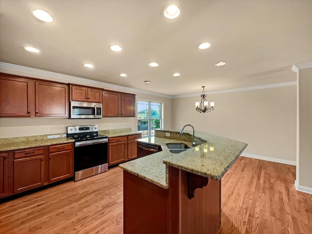 kitchen with pendant lighting, sink, an island with sink, light hardwood / wood-style floors, and stainless steel appliances