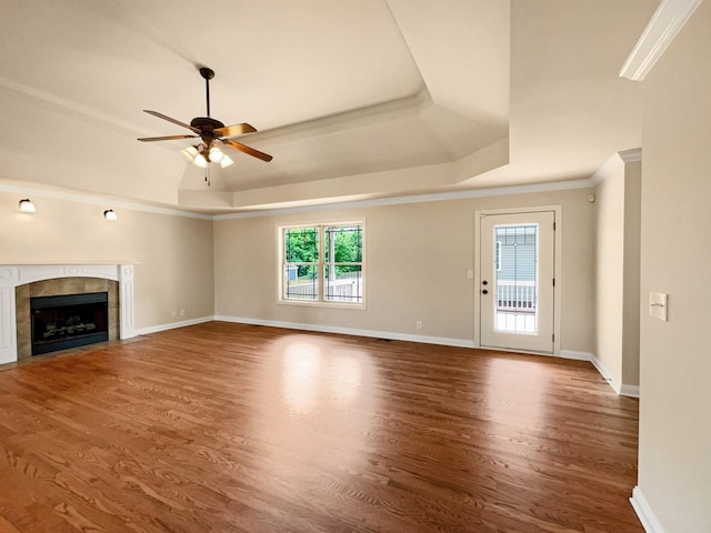 unfurnished living room featuring plenty of natural light, ornamental molding, a tile fireplace, and a tray ceiling