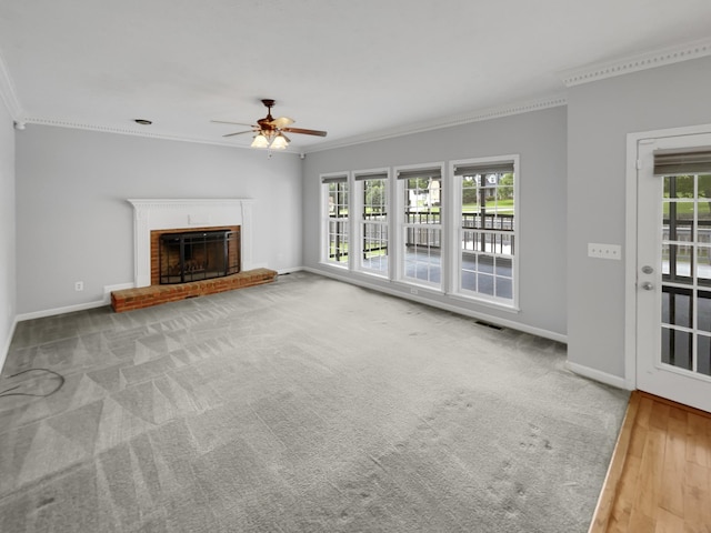 unfurnished living room with ceiling fan, a healthy amount of sunlight, crown molding, and a brick fireplace