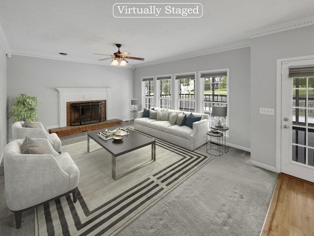 living room with light wood-type flooring, a brick fireplace, ceiling fan, and ornamental molding