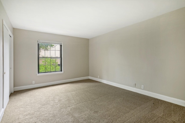 carpeted empty room featuring baseboards