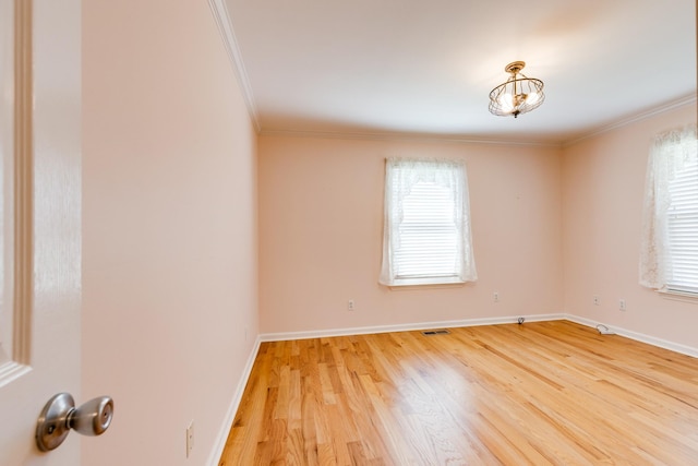 empty room with plenty of natural light, wood-type flooring, and ornamental molding