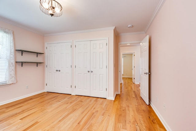 unfurnished bedroom with multiple windows, light hardwood / wood-style flooring, two closets, and ornamental molding