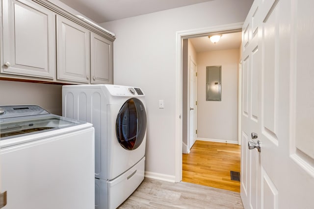 laundry area featuring washer and clothes dryer, cabinets, light wood-type flooring, and electric panel