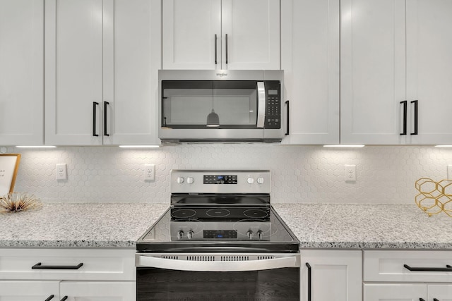 kitchen with light stone counters, stainless steel appliances, decorative backsplash, and white cabinets