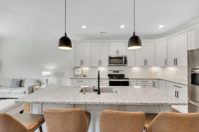 kitchen with sink, white cabinetry, a kitchen breakfast bar, pendant lighting, and stainless steel appliances