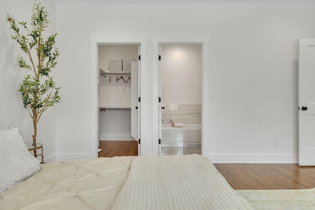 bedroom with hardwood / wood-style flooring, a walk in closet, ensuite bath, and a closet