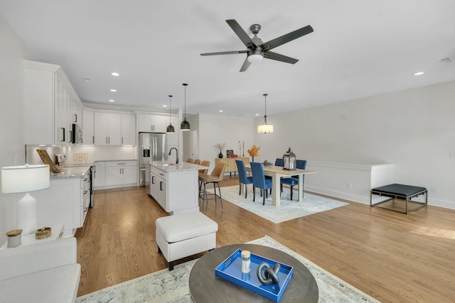 living room with sink, light hardwood / wood-style flooring, and ceiling fan