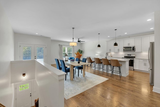 dining area with sink, light wood-type flooring, and french doors