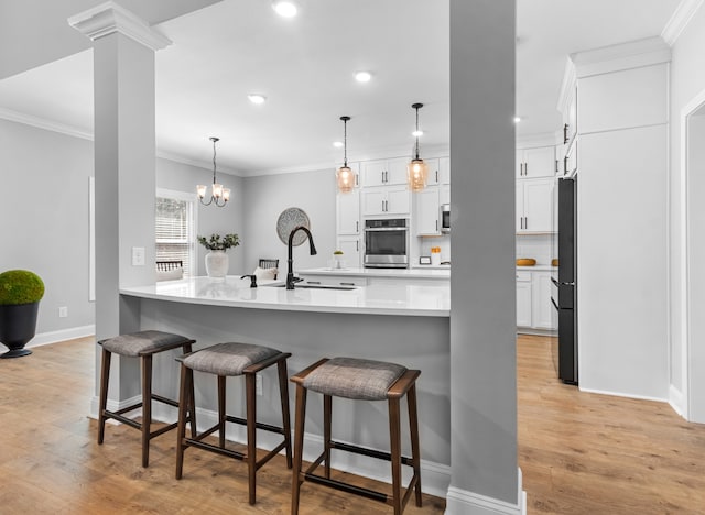 kitchen featuring stainless steel oven, backsplash, white cabinets, refrigerator, and sink