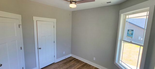 unfurnished bedroom with ceiling fan, multiple windows, and dark hardwood / wood-style flooring