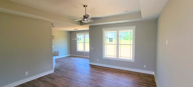 empty room featuring ceiling fan, a raised ceiling, and dark hardwood / wood-style floors