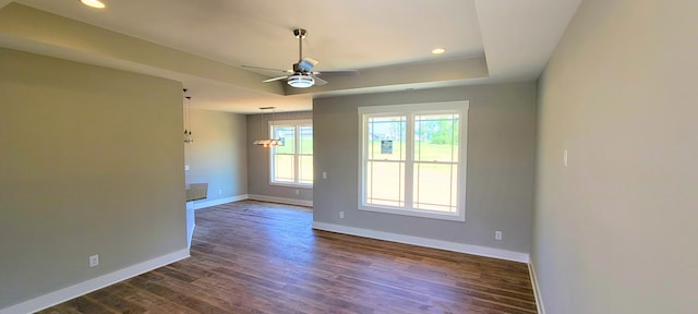 empty room with ceiling fan, a raised ceiling, and dark hardwood / wood-style flooring