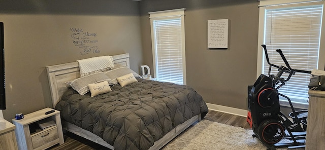 bedroom with dark hardwood / wood-style floors and multiple windows