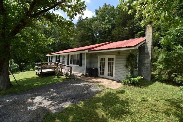 view of front of house with french doors, a wooden deck, and a front lawn