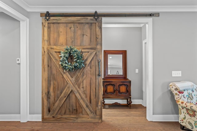 room details with a barn door, wood-type flooring, and ornamental molding