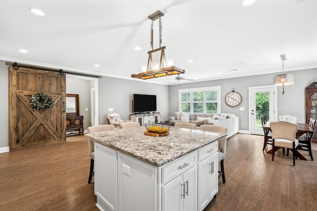 kitchen featuring white cabinets, pendant lighting, a barn door, and a kitchen breakfast bar