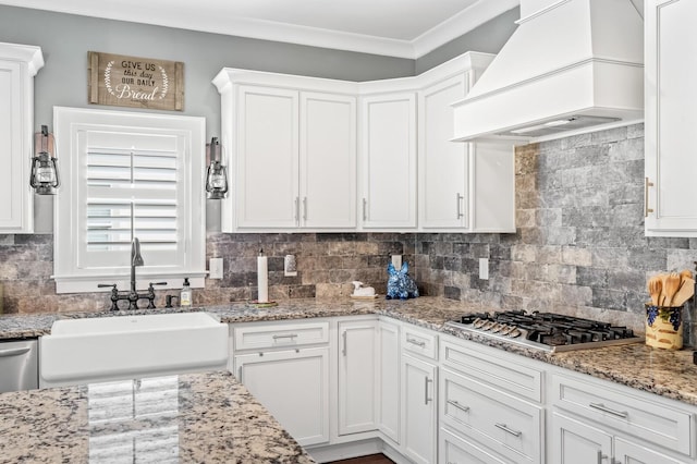 kitchen with premium range hood, sink, tasteful backsplash, white cabinetry, and stainless steel gas cooktop