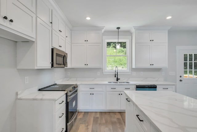 kitchen with pendant lighting, sink, light wood-type flooring, white cabinetry, and stainless steel appliances