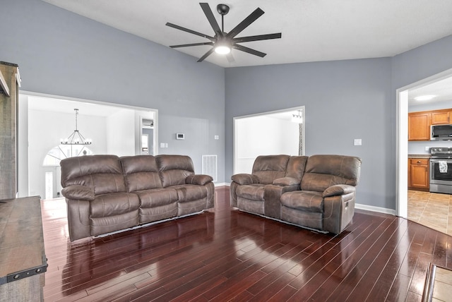 living room featuring ceiling fan with notable chandelier, lofted ceiling, and dark hardwood / wood-style floors