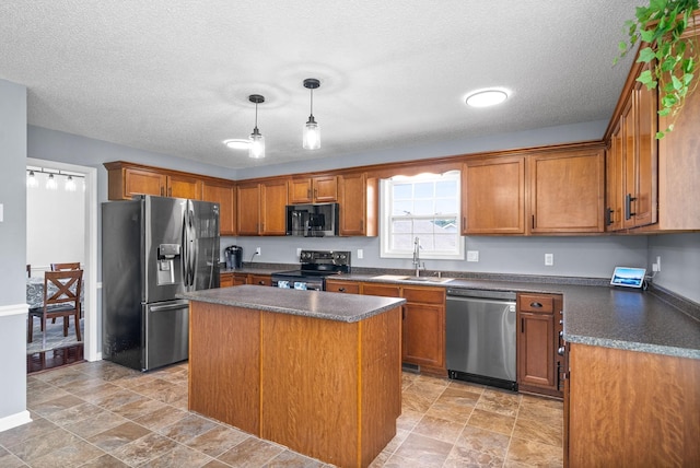 kitchen featuring stainless steel appliances, a center island, a textured ceiling, sink, and decorative light fixtures