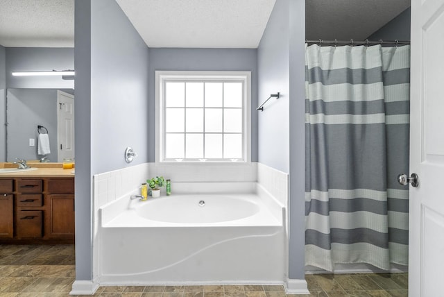 bathroom with a textured ceiling, independent shower and bath, and vanity