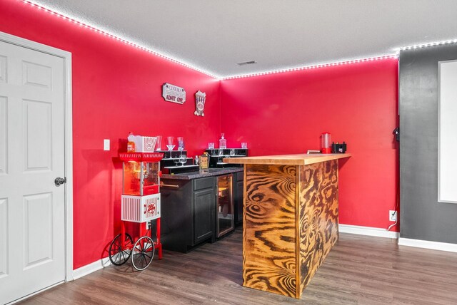 bar featuring a textured ceiling, dark hardwood / wood-style flooring, and wine cooler