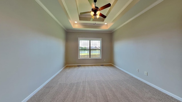 carpeted spare room featuring a tray ceiling, crown molding, and ceiling fan