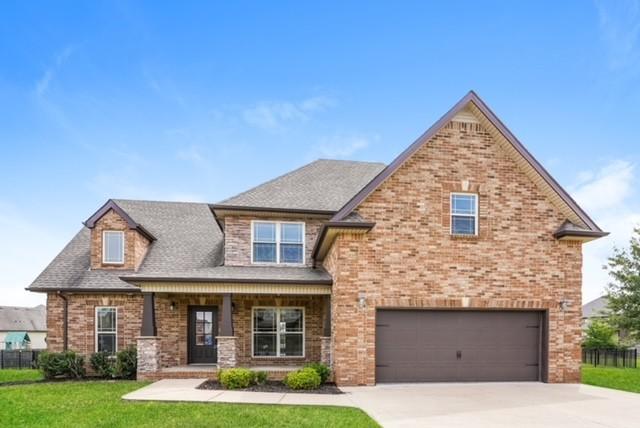 view of front of property featuring covered porch, a front yard, and a garage